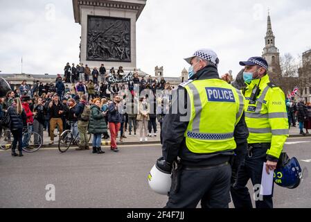 Police officers watching on as protesters gather in Trafalgar Square at a COVID 19 anti lockdown protest march in Westminster, London, UK. Face masks Stock Photo