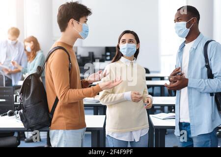 Happy international students wearing medical masks and talking Stock Photo