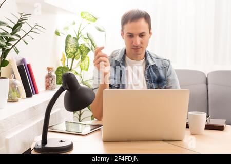 technology, remote job and lifestyle concept - happy man with laptop computer having video chat and waving hand at home office Stock Photo