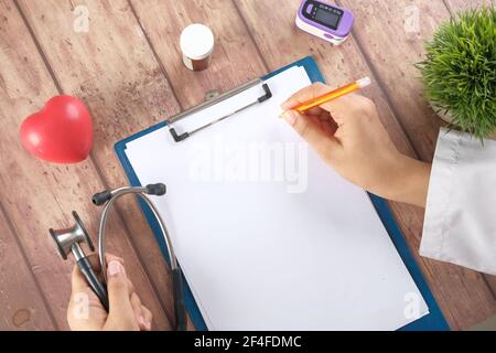 female doctor hand writing prescription on desk, top view  Stock Photo