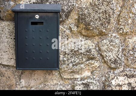 Black metal mailbox attached on cottage wall house. Rural Communications concept Stock Photo