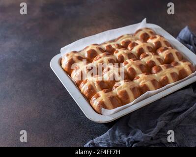 Homemade Hot Cross Buns in a metal baking dish on brown background. Traditional Easter food. Easter holiday concept. British food Stock Photo
