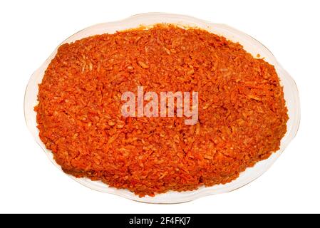 Baked fish fillets in carrot salad without additives on a decorative plate, isolated on a white background with a clipping path, top view. Stock Photo