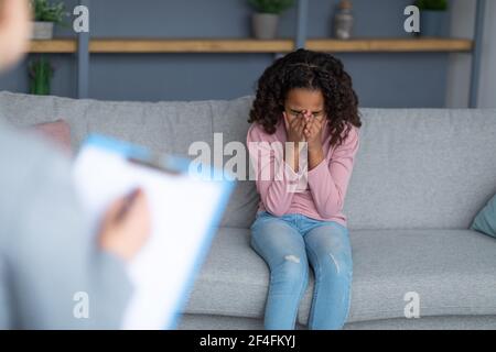 Child psychologist working with teenager, stressed girl crying, covering her face Stock Photo