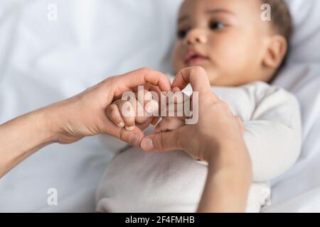 Black mother holding baby's hands in heart shape Stock Photo