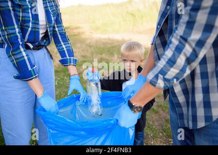 volunteering, charity, people and ecology concept, volunteers using garbage bag while collecting litter Stock Photo