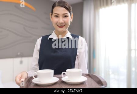 Hotel service concept. Chambermaid holding tray with cup of coffee Stock Photo