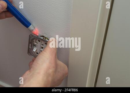 Сlose up view of man checks voltage in the electrical outlet. Sweden. Stock Photo