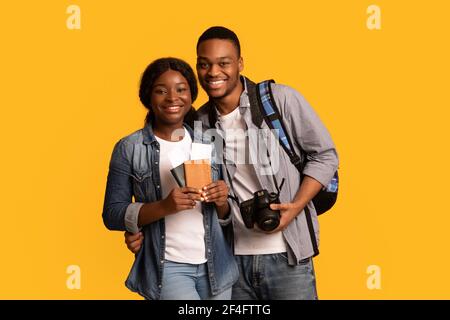 Tourists Couple. Happy african lovers holding passports with tickets and photo camera Stock Photo