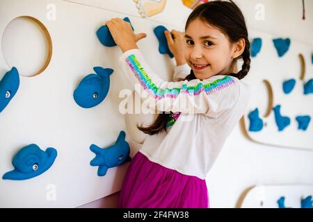 The little girl is climbing on the wall in the playroom Stock Photo