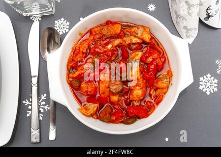 Raw herring in oil with paprika and cucumber, standing in a white plate on the Christmas table in Poland. Stock Photo