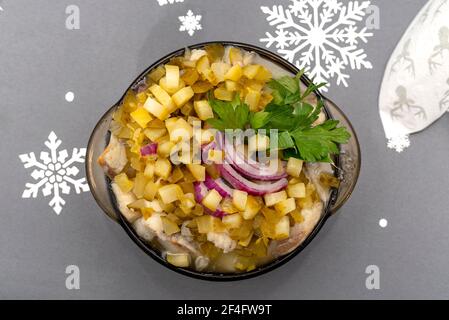 Raw herring in oil with onion, cucumber and parsley, standing in a bowl on the holiday table in Poland. Stock Photo