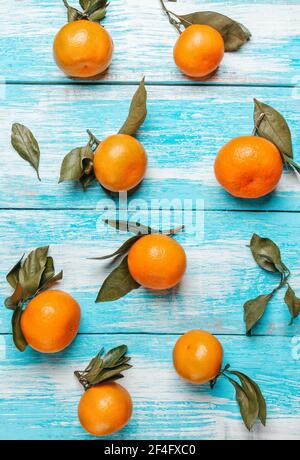 Tangerines with leaves lie on a wooden blue table. Strips of boards horizontally. Vertical orientation. Stock Photo