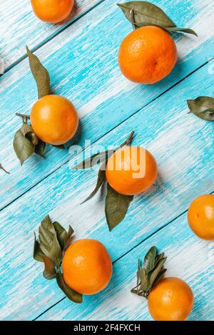 Tangerines with leaves lie on a wooden blue table. Strips of boards on the diagonal. Vertical orientation. Stock Photo