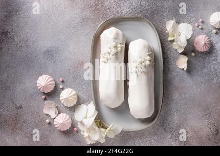 chocolate eclairs and hydrangea flowers, sweets on pink background Stock Photo