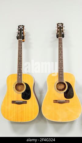 West Islip, New York, USA - 30 November 2018: Two guitars hanging next to each other on a white wall. Stock Photo