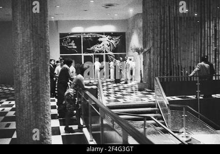 Night-shot of people loitering in the brightly lit foyer of the Habana Libre Hotel, Havana, Cuba, 1964. From the Deena Stryker photographs collection. () Stock Photo