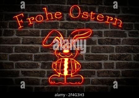 Leuchtreklame Frohe Ostern, darunter befindet sich ein Osterhase der ein Osterei hält | Illuminated sign Happy Easter, below is an Easter bunny holdin Stock Photo