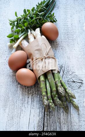 Group of raw asparagus with eggs, onions and herbs on wooden background. Directly above. Stock Photo