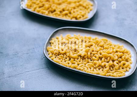 Wheat raw Italian pasta in plates isolated on blue background.. Stock Photo