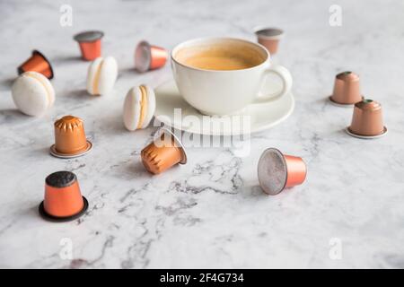 Cup of espresso, black coffee served with pods and capsules on marble table.Collection of espresso coffee capsules.Caffeine, hot drinks and objects Stock Photo