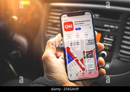 Kharkov, Ukraine - March 17, 2021: Businessman using smartphone with CNN News app on screen Stock Photo