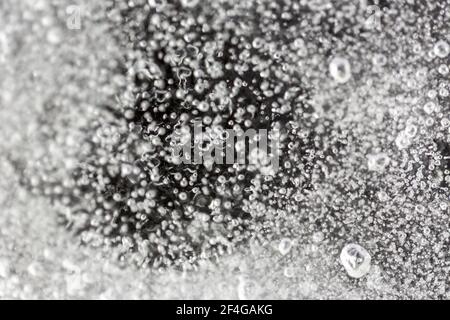 Macro shot of tiny air bubbles trapped in a sheet of ice in the garden, shot with a flash strobe light to illuminate the ice Stock Photo