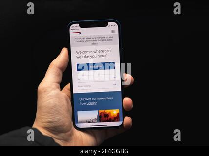 Kharkov, Ukraine - March 17, 2021: British Airways application, man booking flight tickets by using mobile app Stock Photo