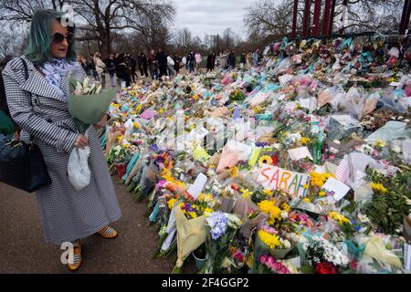 A woman holding flowers looks at floral tributes left at the bandstand in Clapham Common, London, for Sarah Everard. Pc Wayne Couzens, 48, appeared at the Old Bailey in London charged with the kidnap and murder of the 33-year-old. Picture date: Sunday March 21, 2021.