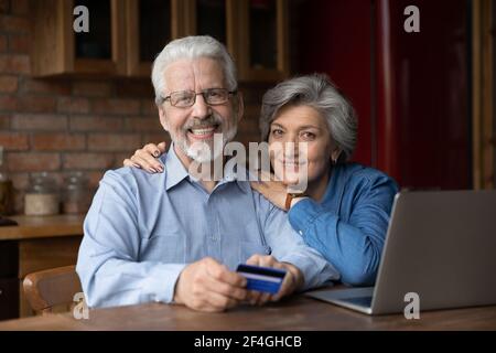 Senior spouses digital bank clients holding credit card paying online Stock Photo