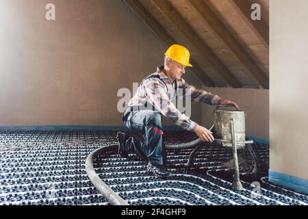 Worker on construction site installing pipes for underfloor heating Stock Photo