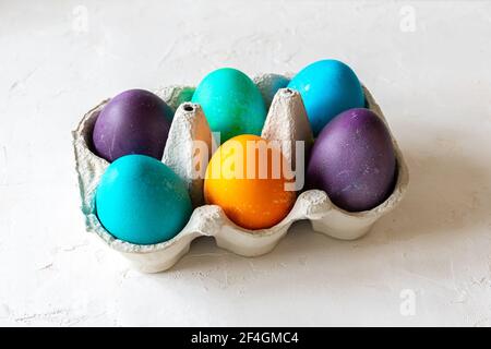 Colorful Easter Eggs in yellow, green, purple, blue and turquoise in an egg carton. Stock Photo