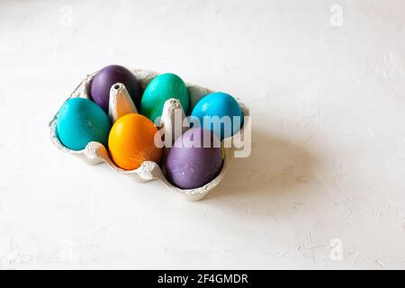 Colorful Easter Eggs in yellow, green, purple, blue and turquoise in an egg carton. Stock Photo