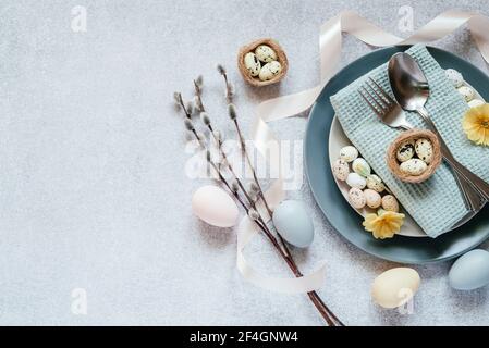 Easter table setting ideas, minimal decoration - Easter eggs, willow catkin branches, bird's nest on light gray background with copy space Stock Photo