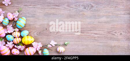 Happy Easter background with pink; yellow, blue eggs and beautiful spring flowers on wooden table. Gift card with colorful easter eggs on old wooden t Stock Photo