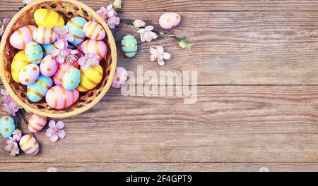 Happy Easter background with pink; yellow, blue eggs and beautiful spring flowers on wooden table. Gift card with colorful easter eggs on old wooden t Stock Photo