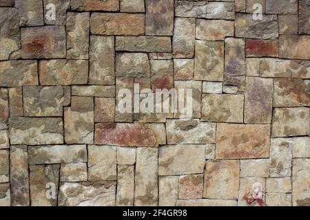Wall of square stones of different sizes. Rectangular tiles of different sizes made of natural red stone Stock Photo