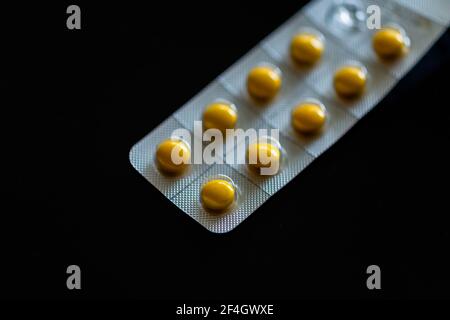 Yellow tablets in blister pack on black background Stock Photo