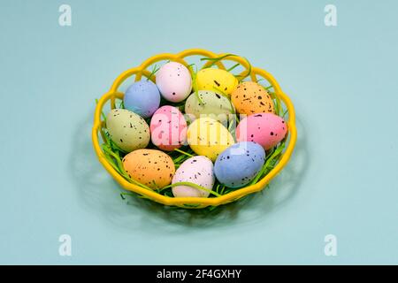 Multicolored Easter eggs in a plastic basket on a blue background. Close-up. View from above. Easter. Stock Photo