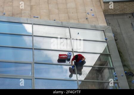 Man cleaning glass roof of modern building. High angle view. Stock Photo