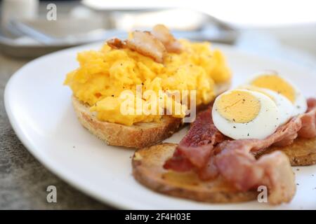 breakfast with scrambled eggs, fried potatoes bacon and shrimp Stock Photo