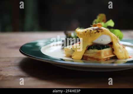 Breakfast food egg benedict , poached egg with yellow sauce with waffle and smoked salmon on wood background Stock Photo