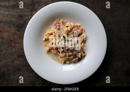 Pasta white sauce with bacon and mushroom on wood background in mystic light Stock Photo