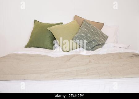 modern bedroom with green pillows on bed.Comfortable bed with new pistachio Cushions , beige and white linens in modern room interior. Stock Photo