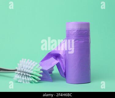plastic brush and skein of purple plastic trash bags with strings on a green background, close up Stock Photo