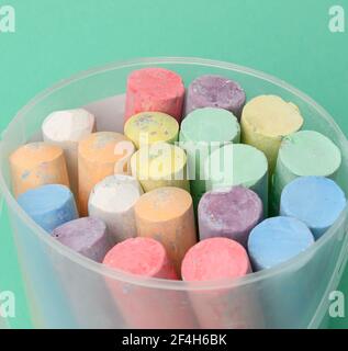 multicolored chalk in a plastic bucket on a green background, close up Stock Photo