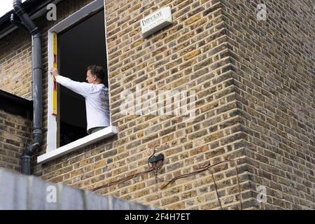 Builder measures the window  opening in bricked wall house, England Stock Photo