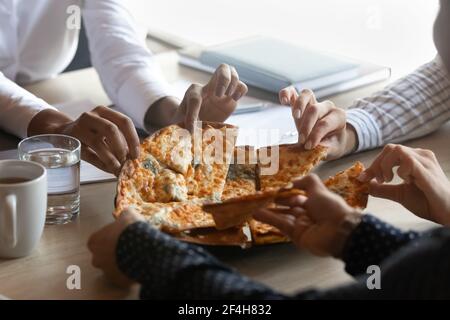 Close up of diverse employees eating tasty pizza in office Stock Photo