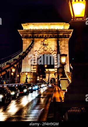 Budapest, Hungary, March 19, 2019: Chain Bridge, illuminated at night by floodlights, and cars on the bridge, in Budapest, Hungary Stock Photo