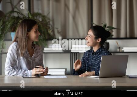 Smiling female colleagues brainstorm cooperate at office meeting Stock Photo